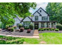 Stunning two-story home boasting a modern black and white exterior, complemented by a beautifully landscaped front yard at 2373 Oak Falls Ln, Buford, GA 30519