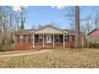 Charming single-story brick home featuring a welcoming front porch and well-maintained landscaping at 3233 Kingfisher Dr, Decatur, GA 30034