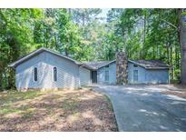 Charming single-story home with stone chimney and private driveway surrounded by mature trees at 4116 Wendell Way, Snellville, GA 30039