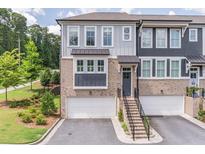 Modern townhome featuring a gray exterior, brick accents, a two-car garage, and a well-manicured front lawn at 370 Thrasher St # 5, Norcross, GA 30071