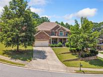 Charming brick home with a well-manicured lawn, mature trees, and attached two-car garage at 4465 Saint Andrews Crest Dr, Cumming, GA 30040