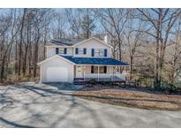 Charming two-story home with a welcoming front porch and a spacious driveway nestled among trees at 169 Holly Ct, Loganville, GA 30052