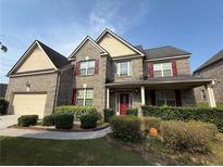 Two-story brick home with red shutters, covered front porch, manicured lawn and landscaping at 3139 Tuscan Ridge Dr, Snellville, GA 30039