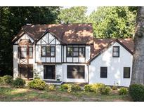 Charming Tudor style home with white exterior, dark trim, and well-manicured landscaping at 4640 Calleigh Way, Snellville, GA 30039