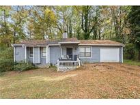 Charming single-story home featuring gray siding, front porch and attached garage, surrounded by mature trees at 1496 Meadowlark Dr, Decatur, GA 30032