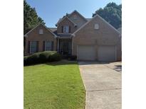 Charming two-story brick home featuring an attached two-car garage and well-manicured lawn at 2580 Three Wood Dr, Villa Rica, GA 30180