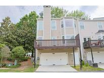 Exterior view of a townhome featuring a two-car garage, a balcony, and neutral-colored siding at 3761 Lake Point Blvd, Suwanee, GA 30024