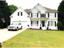 Charming two-story home featuring a well-manicured lawn, black shuttered windows, and a car parked in the driveway at 6265 Lake Windsor Pkwy, Buford, GA 30518