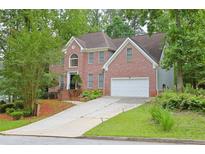 Charming two-story brick home with a two-car garage and a beautifully landscaped front yard at 7435 Woodruff Way, Stone Mountain, GA 30087