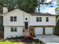 Charming two-story home featuring a stone facade, two-car garage, fresh landscaping, and inviting front entrance at 975 Memory Ln, Lawrenceville, GA 30044