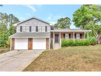 Charming two-story home with stone and vinyl siding, double garage, front porch and landscaped yard at 8989 Teal Ln, Jonesboro, GA 30236