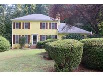 Charming yellow two-story home with red shutters, mature landscaping and a well-maintained lawn at 150 Ashley Dr, Fayetteville, GA 30214