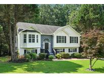 Charming home with white siding, black shutters, and a beautifully landscaped front yard with mature trees at 4076 Whistler Dr, Douglasville, GA 30135