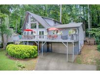 Gray home featuring a spacious wrap-around deck overlooking a lush, wooded lot at 8531 Lake Dr, Snellville, GA 30039