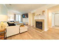 Bright living room featuring hardwood floors, a cozy fireplace, and a comfortable seating area with a large sectional sofa at 3677 Blackshear Ct, Duluth, GA 30096