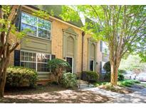 Inviting brick townhome featuring a well-manicured lawn and mature shade trees for a comfortable outdoor living space at 6980 Roswell Rd # N5, Atlanta, GA 30328