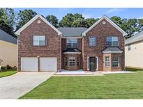 Charming two-story brick home featuring a well-manicured lawn, two-car garage, and lovely front yard landscaping at 802 Cormac Dr, Riverdale, GA 30296