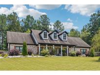Charming brick home features a long, covered front porch, dormer windows and a lush green lawn at 1369 Sierra Ridge Pl, Loganville, GA 30052