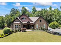 Beautiful brick home with manicured lawn and mature trees, featuring a covered front porch and lush landscaping at 1005 Renfroe Lake Dr, Auburn, GA 30011