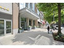 Modern building entrance with large glass windows, planters, and sidewalk with pedestrian at 855 Peachtree Ne St # 2205, Atlanta, GA 30308