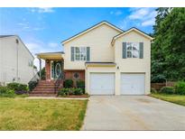 Charming two-story home featuring a two-car garage, brick accents, and a well-maintained front yard at 5718 Hidden Brook Cir, Atlanta, GA 30349