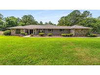 Charming brick and stone home with a well-manicured lawn and mature trees at 1535 Pathfinder Sw Way, Lilburn, GA 30047