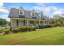 Charming brick home with a well-manicured lawn, a welcoming front porch, and dormer windows at 3906 Laurens Ln, Snellville, GA 30039