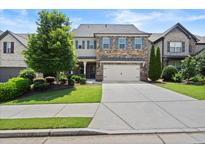 Charming two-story home featuring a stone and siding facade, a two-car garage, and a well-manicured lawn at 4452 Thach Ave, Sugar Hill, GA 30518