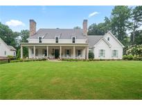 Expansive front yard of charming two-story home with a covered porch and classic rocking chairs at 104 Trinity Hollow Dr, Canton, GA 30115