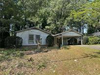 Modest single-story home featuring simple landscaping, a carport and mature trees providing shade at 512 Rockborough Ter, Stone Mountain, GA 30083