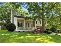 Charming single Gathering home boasts a welcoming front porch, manicured lawn, and mature trees at 2995 Ivy Mill Dr, Buford, GA 30519