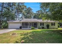 Charming single-story home features a screened-in front porch, attached garage, and a spacious front lawn at 2780 Highpoint Rd, Snellville, GA 30078