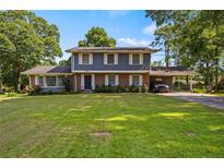 Charming two-story home with a lush green lawn, mature trees and a covered carport at 1809 Claron Ave, Conley, GA 30288
