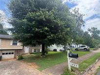 Split-level home with a large tree in the front yard and a driveway leading to an attached garage at , Roswell, GA 30076