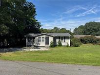 Charming single-story home featuring a well-maintained lawn and mature trees on a sunny day at 6261 Pinegrove Rd, Riverdale, GA 30274