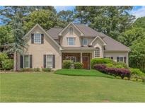 Charming two-story home featuring a well-manicured lawn and inviting front porch, set amongst mature trees and landscaping at 1605 Little Lisa Ln, Snellville, GA 30078