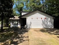 Charming single-story home featuring white siding, black trim, and a spacious driveway, surrounded by mature trees at 1771 Kristi Dr, Lawrenceville, GA 30043