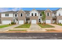 Charming townhouse exterior with brick accents, attached garage, and well-manicured lawns at 357 Navigator Ln, Mcdonough, GA 30253