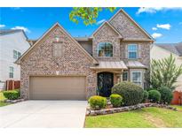 Charming two-story brick home featuring a manicured lawn and a two-car garage, all under a beautiful blue sky at 1146 Simonton Peak Way, Lawrenceville, GA 30045
