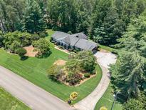 A lovely single-story home features a lush green lawn, mature trees, and a circular driveway at 1725 Mountainside Dr, Cumming, GA 30040