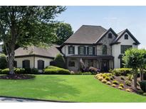 Beautiful two-story home with a manicured lawn, stone accents, and a welcoming front porch with lush, mature landscaping at 5995 Ettington Dr, Suwanee, GA 30024