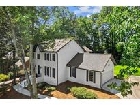 Elegant two-story home with painted brick exterior and black shutters surrounded by mature trees at 4745 Masters Ct, Duluth, GA 30096