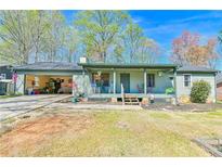 Charming single-story home with a covered front porch and open garage on a sunny day at 5774 Harbor Dr, Buford, GA 30518