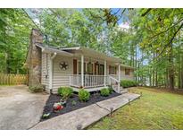Charming home featuring a stone chimney, covered front porch, and lovely landscaping at 5527 Centry Dr, Villa Rica, GA 30180