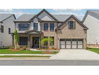 A beautiful two-story brick home with a well-manicured lawn and a two-car garage at 5340 Candun Cir, Sugar Hill, GA 30518