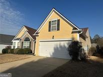Charming yellow home with well-manicured landscaping and a two-car garage on a sunny day at 1060 S Creek Dr, Villa Rica, GA 30180