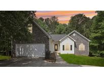 Charming single-Gathering home featuring a two-car garage, stone accents, and a well-maintained front lawn at 1945 Grayson Oaks Ct, Lawrenceville, GA 30045