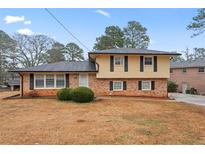 Charming two-story home featuring a brick facade, yellow siding, and manicured front yard, perfect for curb appeal at 2002 Twin Falls Rd, Decatur, GA 30032