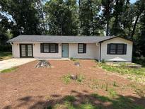 Charming one-story home with a landscaped front yard, dark shutters, and a light blue door at 1087 W Adrian Sw Cir, Conyers, GA 30094