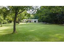 Spacious front yard with well-manicured lawn and mature trees surrounding a charming yellow home at 1205 Humphries Nw Rd, Conyers, GA 30012